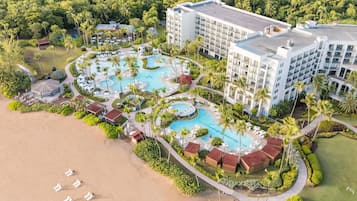 Een resort met meerdere zwembaden, een strand en een groot hotelgebouw.