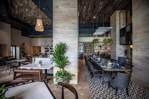 A spacious restaurant with high ceilings, wooden beams, and modern furnishings.