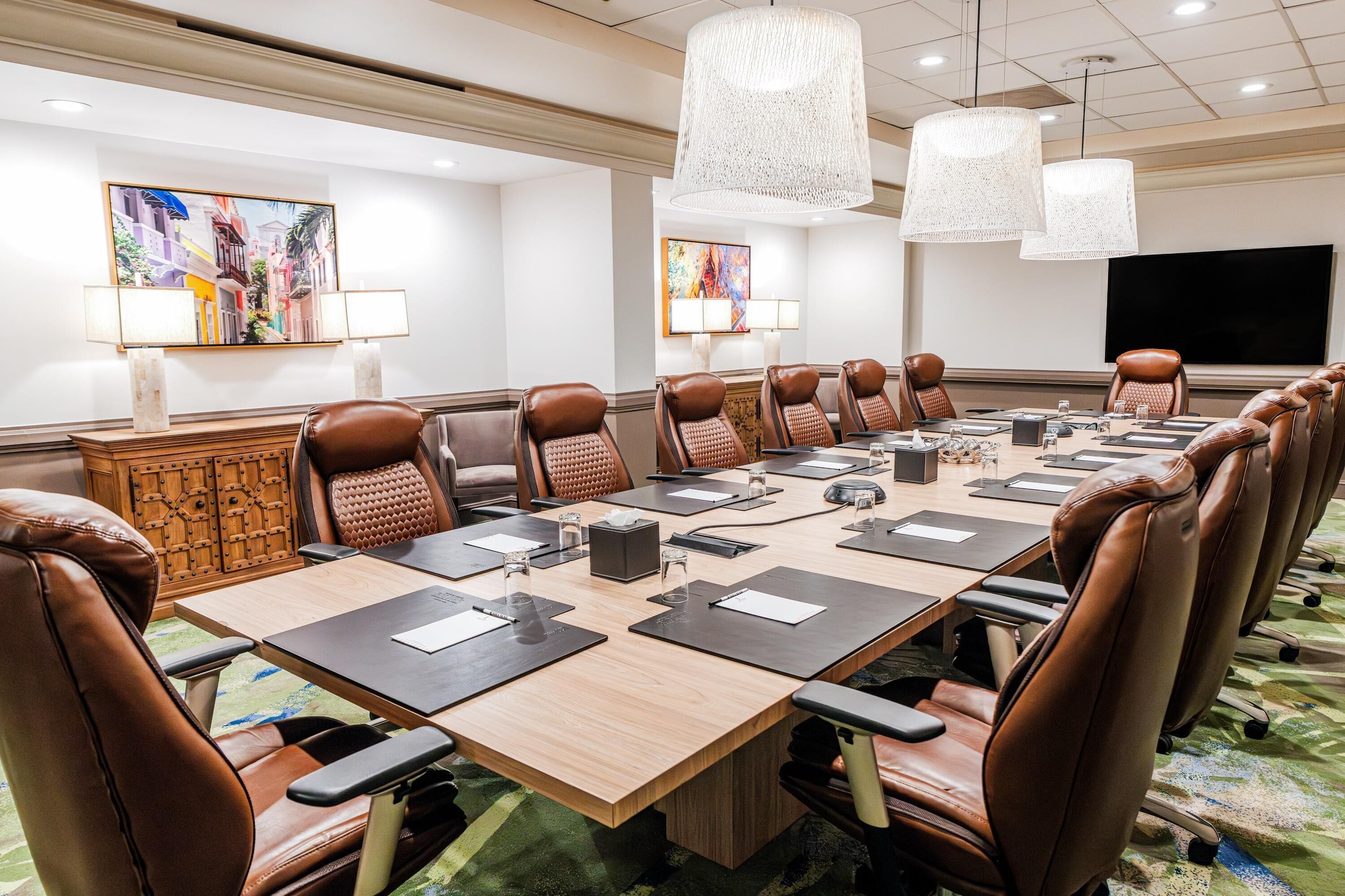 Un salón de conferencias con una larga mesa, sillas de cuero y dos candelabros.