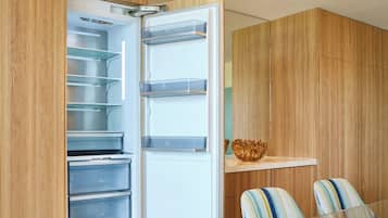 Eine moderne Küche mit integriertem Kühlschrank, übersichtlichen Regalen und einer Holzwandverkleidung.