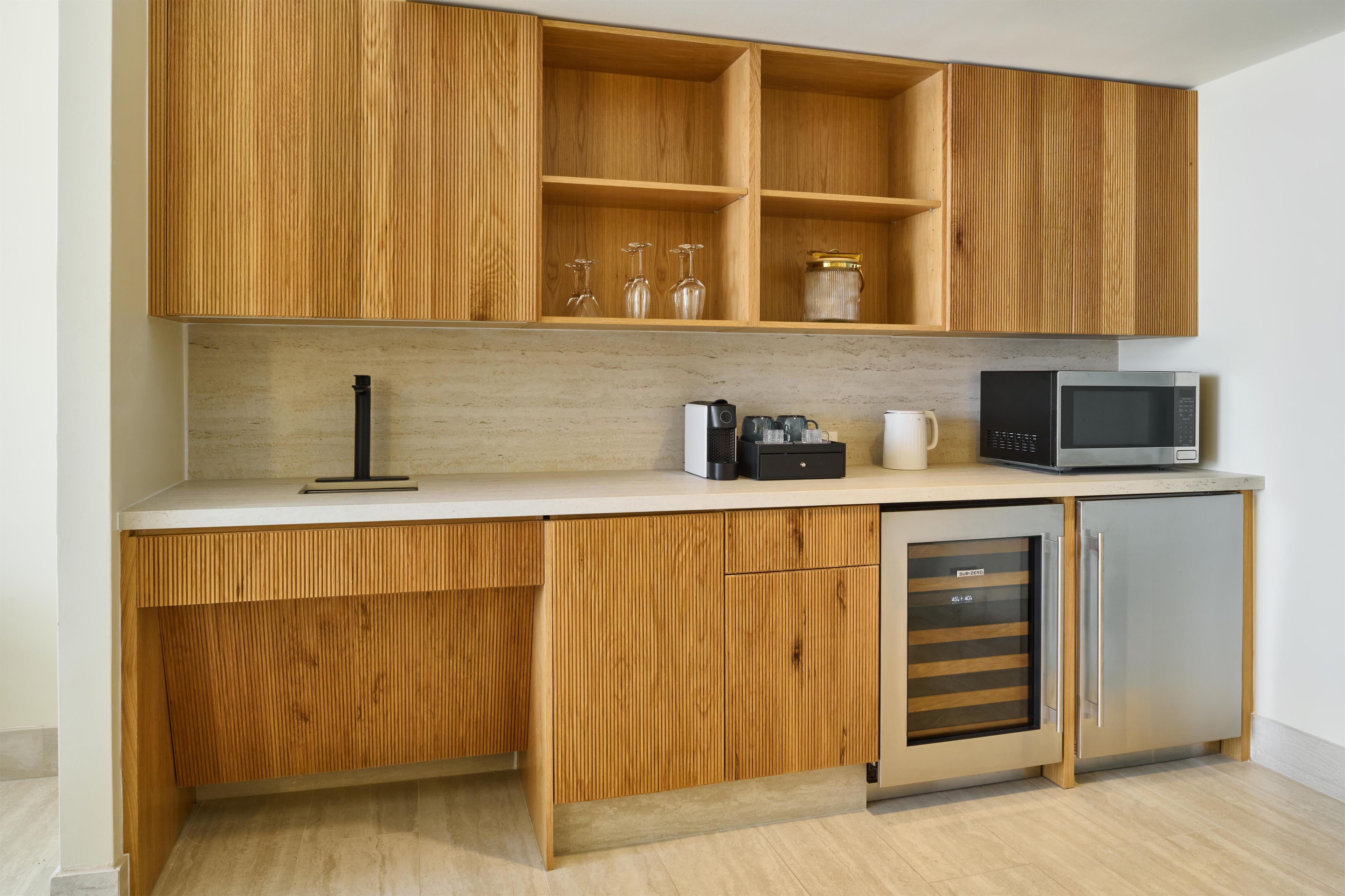 Une cuisine dotée de meubles en bois, d’un plan de travail, d’un four à micro-ondes, d’une machine à café et d’un lave-vaisselle.