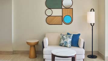 Un salon moderne avec un canapé beige, une table basse ronde, une table d’appoint en bois et un lampadaire.