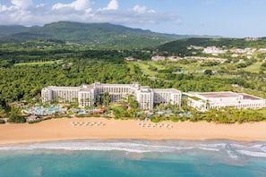 Ein Resort mit mehreren Gebäuden, einer Strandlage und umgebender Bepflanzung.
