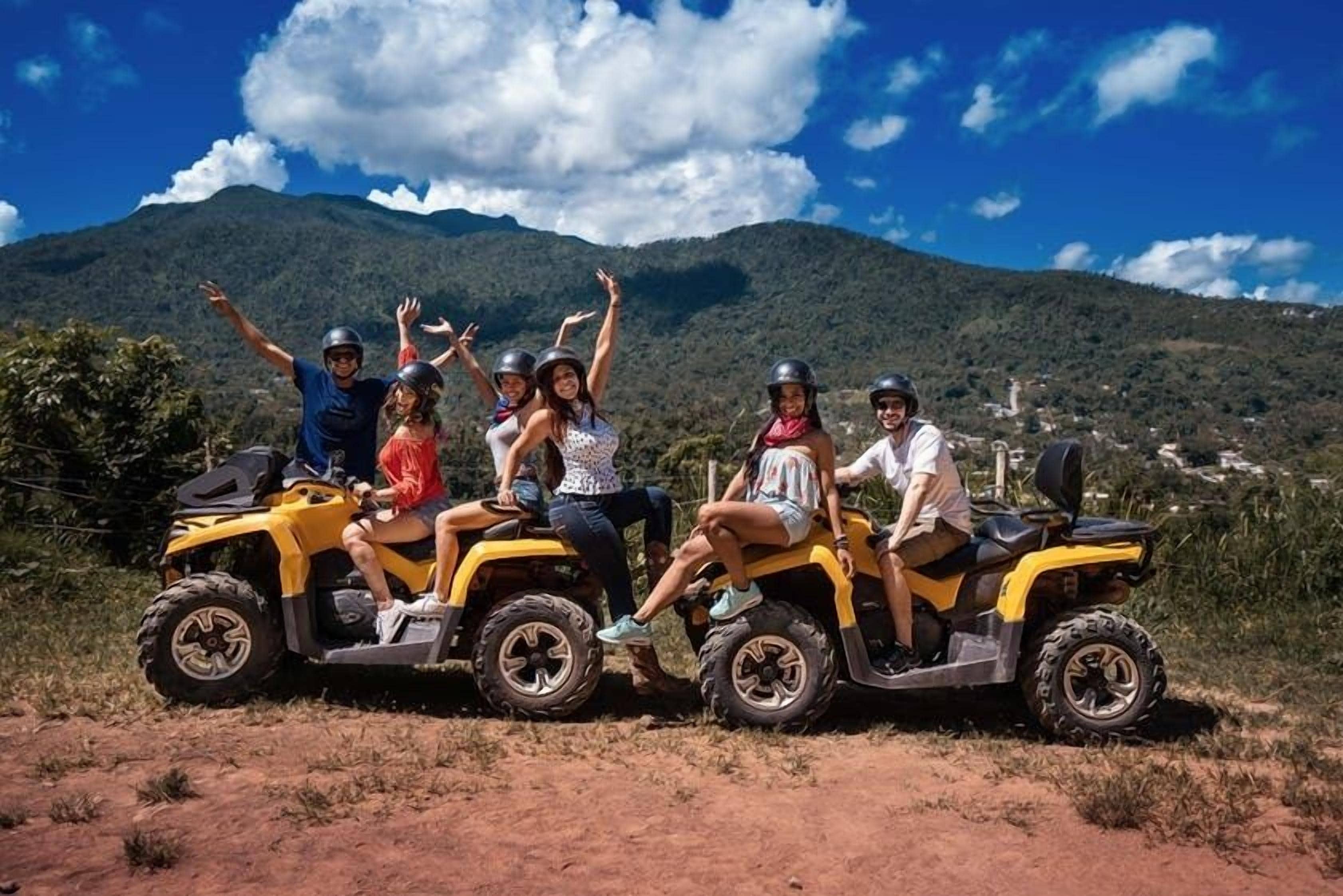 Un grupo de personas manejando vehículos todo terreno en un entorno natural, con montañas al fondo.
