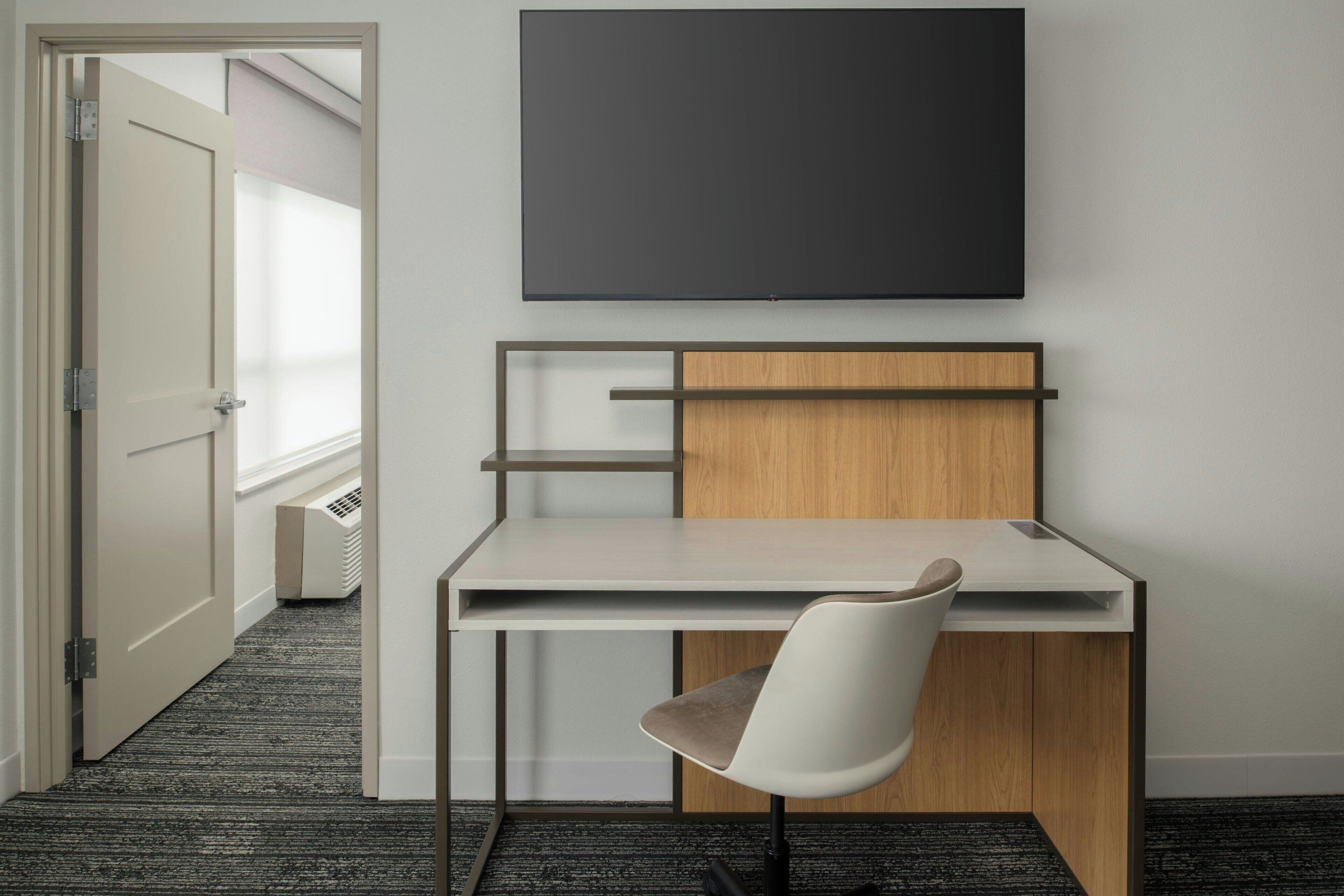 A modern office space with a desk, chair, and a mounted flat-screen TV.