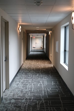 Corridors feature carpeted floors with a geometric pattern and wall-mounted lighting.