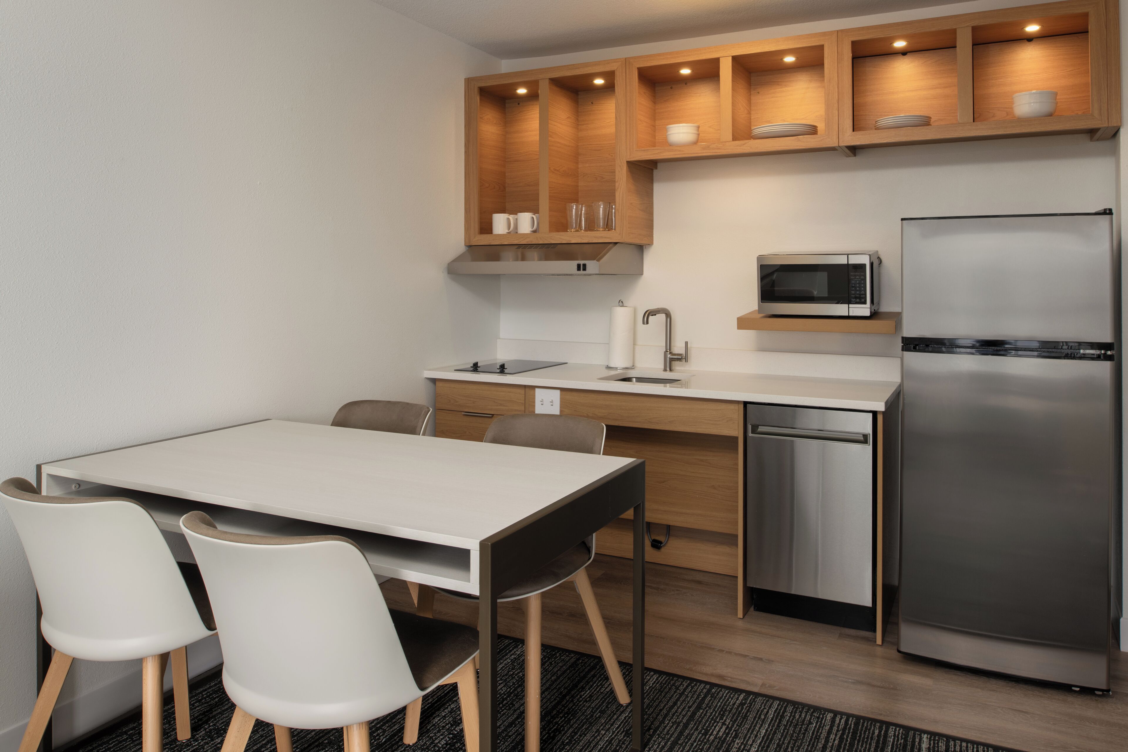 A compact kitchen with a white countertop, stainless steel appliances, and wooden cabinets.