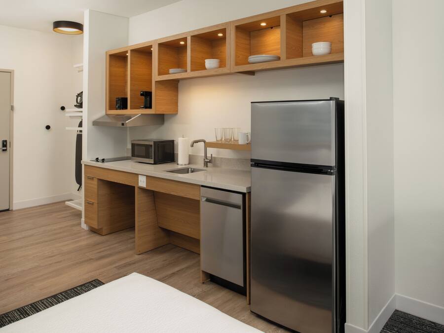 A modern kitchen with a stainless steel refrigerator, wooden cabinets, a microwave, and a dishwasher.