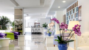 A modern lobby with a bar area, seating arrangements, and decorative plants. - Hotel Caravel (Sant'Agnello)