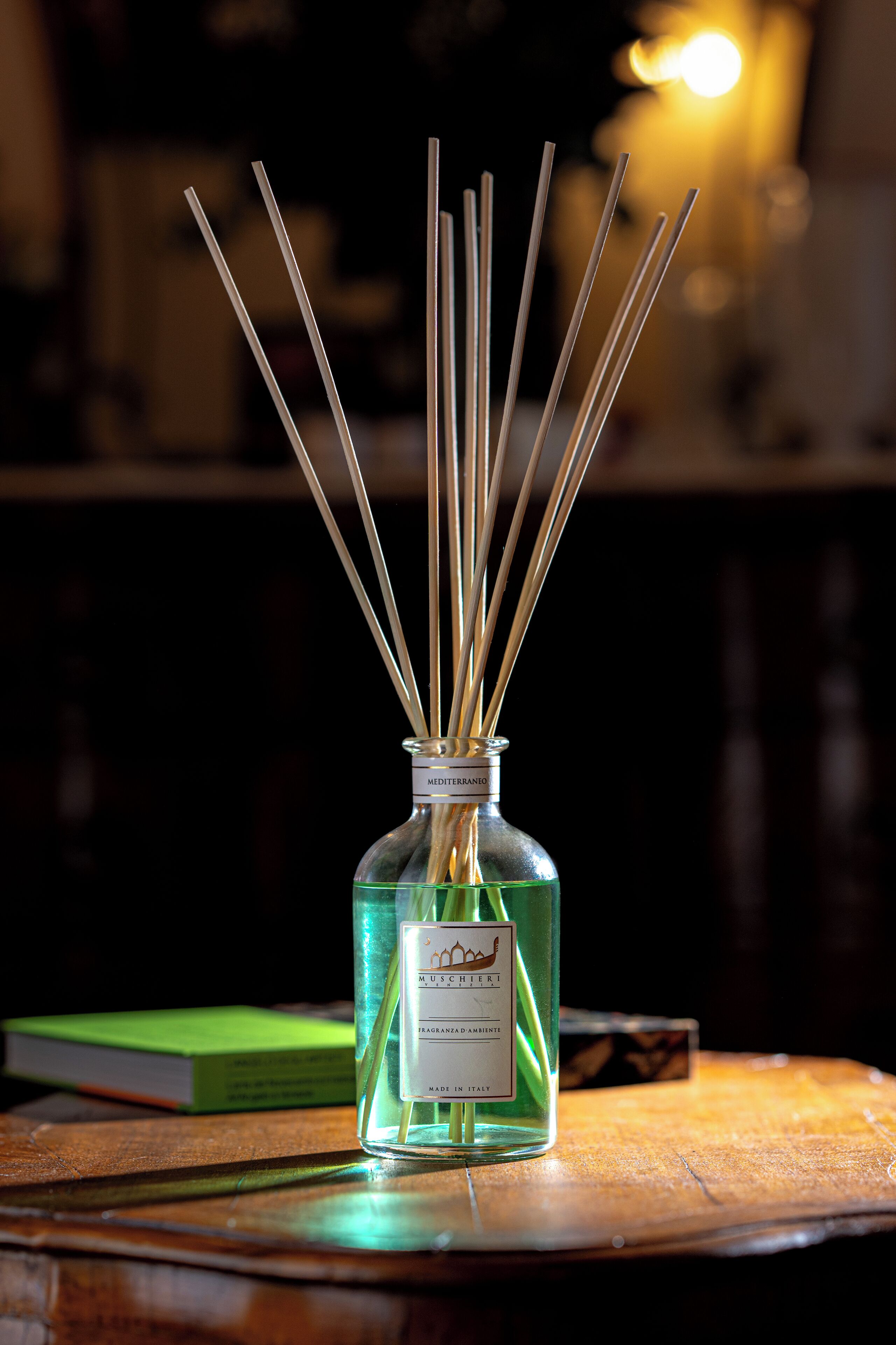 A bottle of reed diffuser with multiple reeds on a wooden surface.