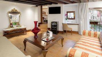 A living room with a wooden coffee table, a red vase, a sofa, a TV, and a staircase leading to another room.