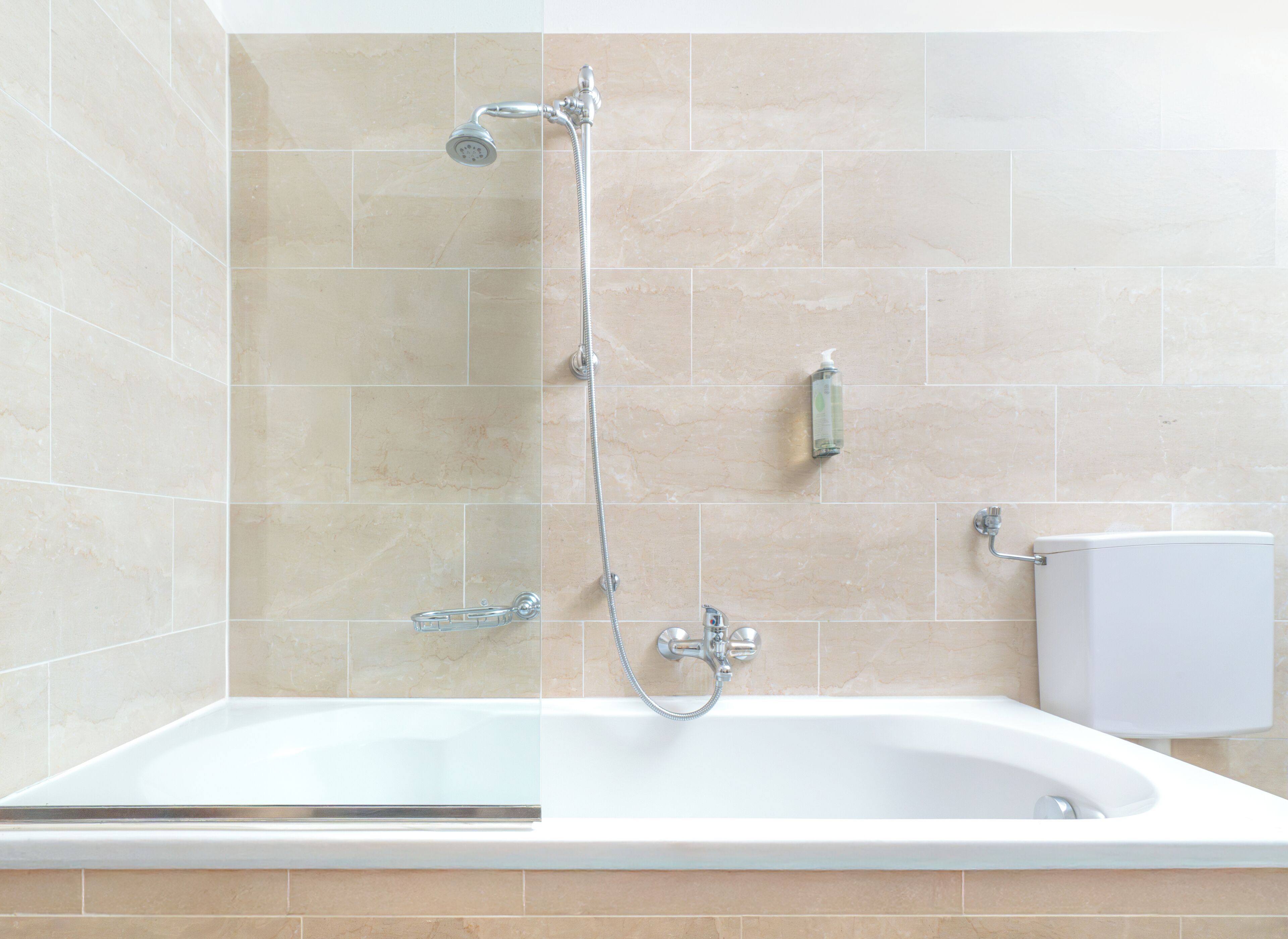 A modern bathroom with a freestanding bathtub, a handheld showerhead, and a wall-mounted toilet.