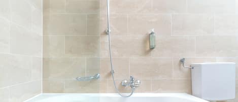A modern bathroom with a freestanding bathtub, a handheld showerhead, and a wall-mounted toilet.
