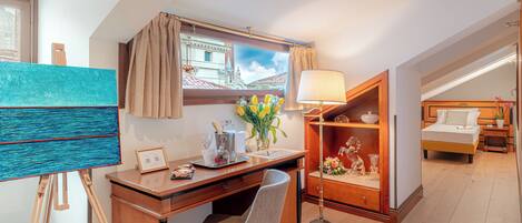 Une chambre d’hôtel équipée d’un bureau, d’une chaise, d’une lampe, d’œuvres d’art et d’un lit.