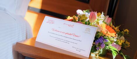 A welcome card and a floral arrangement on a wooden table.