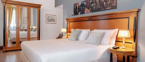 Un cuarto de hotel con una cama grande, dos mesitas de noche con lámparas, un cabecero de madera, un espejo grande y un cuadro en la pared.