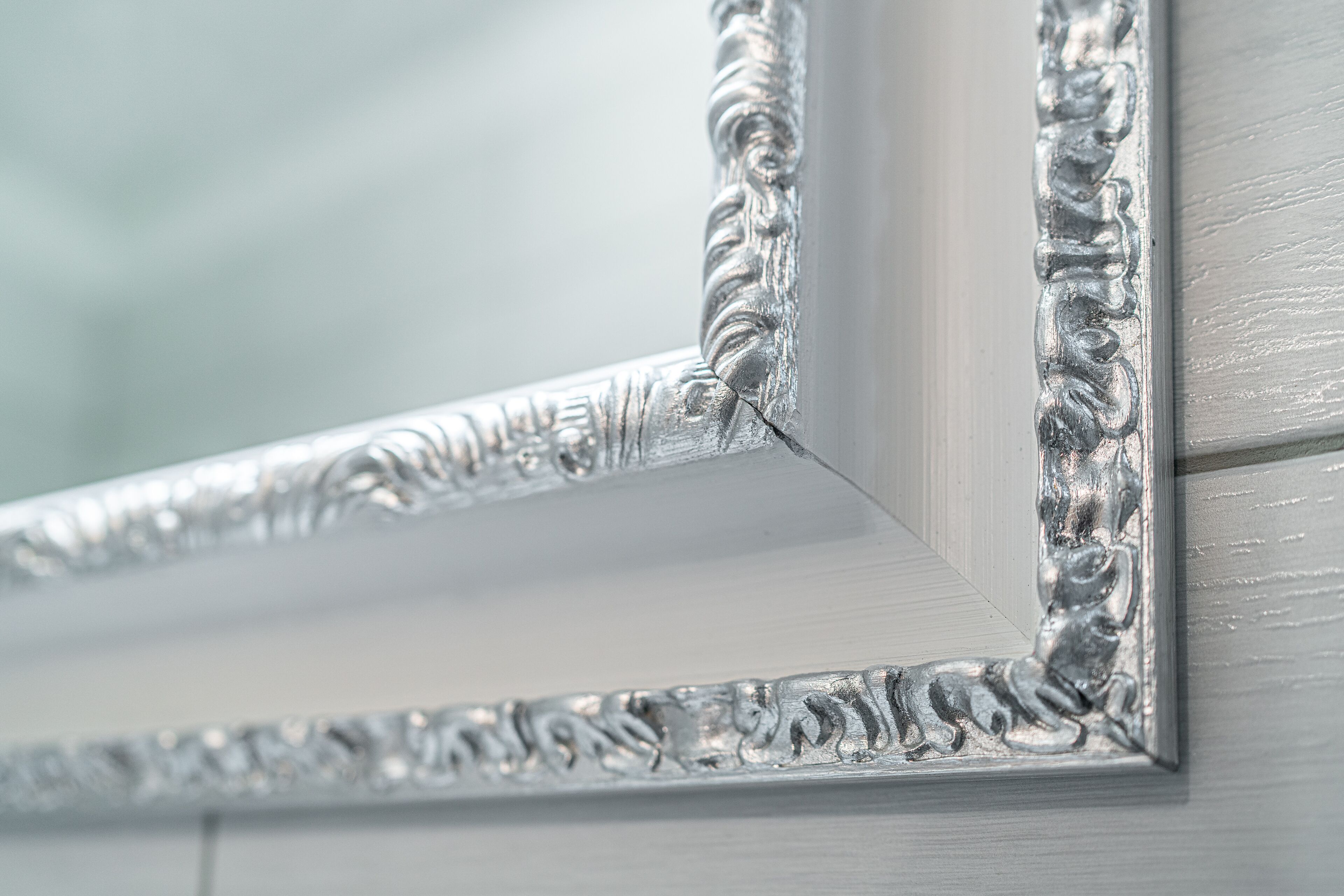 A close-up of a silver-framed mirror with ornate detailing.