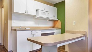 Una cocina con armarios blancos, un microondas y una encimera.
