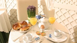 A breakfast table set with croissants, orange juice, a vase of flowers, and a pitcher of milk. - Hotel Valle (Rome)