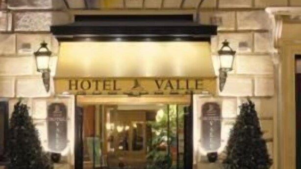 The entrance of Hotel Vallee with a classic facade, double doors, and two potted Christmas trees. - Hotel Valle (Rome)