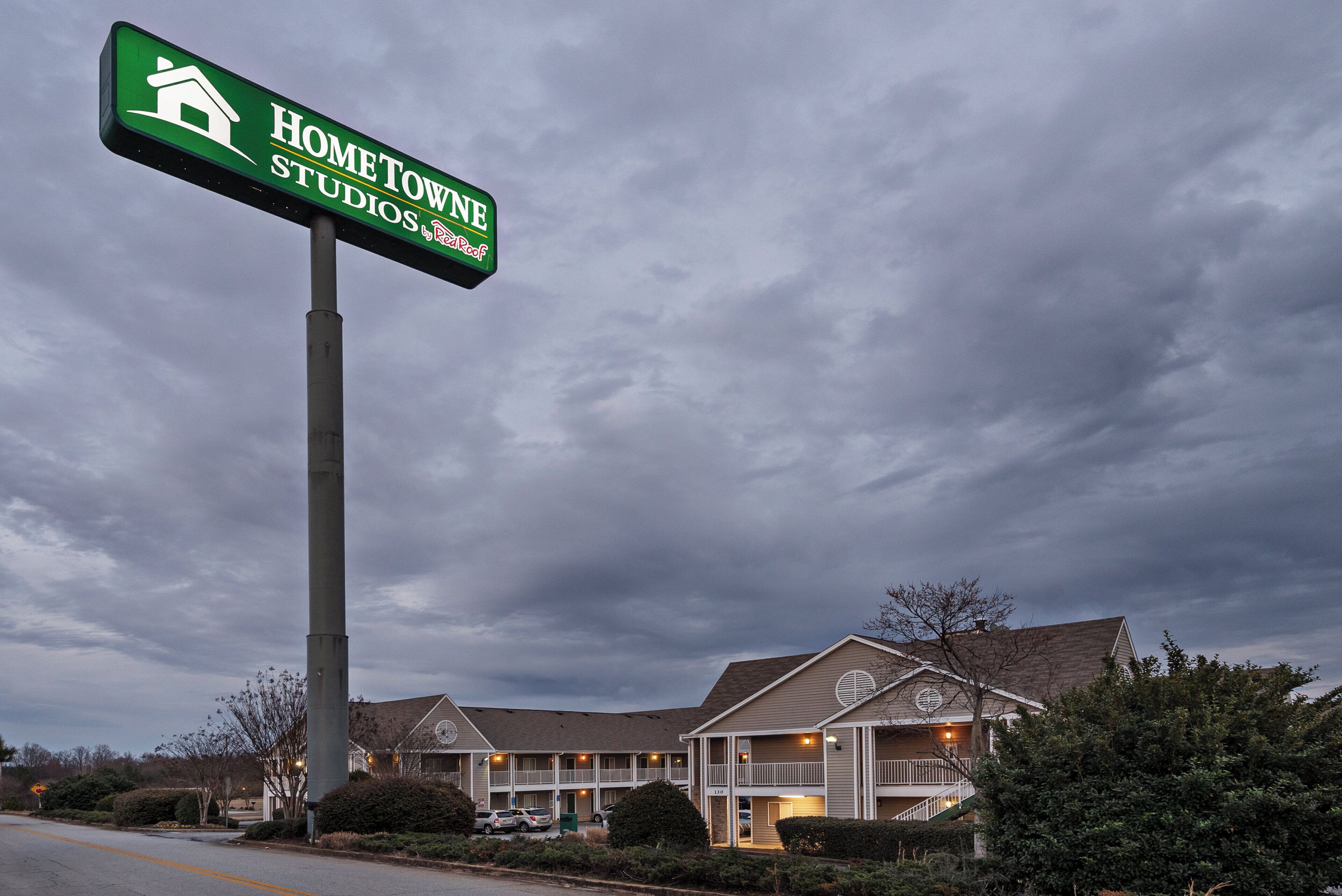 A motel with a large sign advertising 'HOMETOWN STUDIOS by Red Roof.'