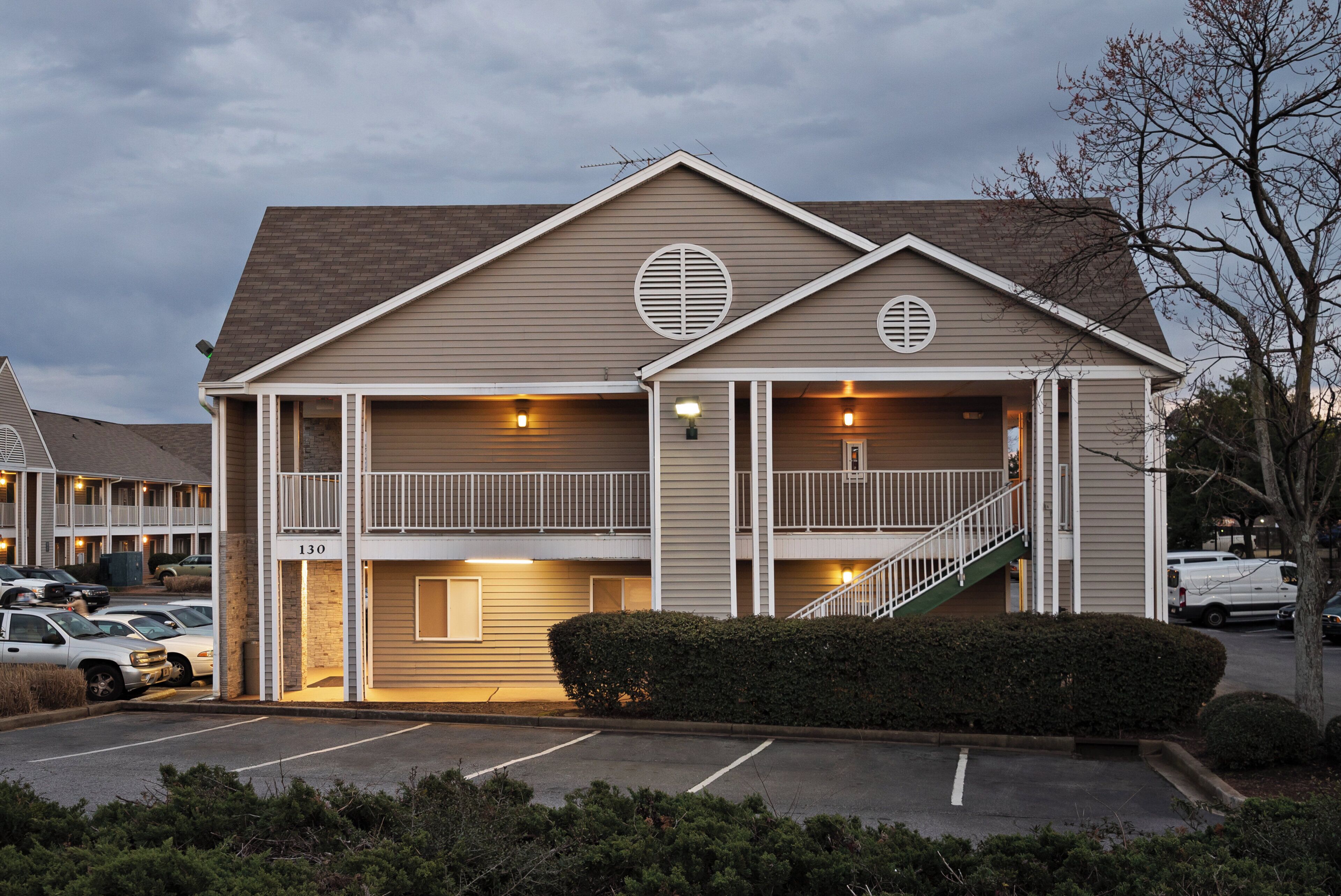 A two-story building with a central staircase, a parking lot, and a clear sky.