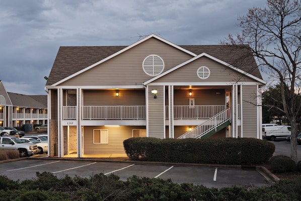 A two-story building with a central staircase, a parking lot, and a clear sky.