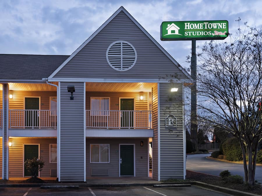 Un motel à deux étages avec une enseigne verte indiquant « HOMETOWNE STUDIOS by Red Roof ».