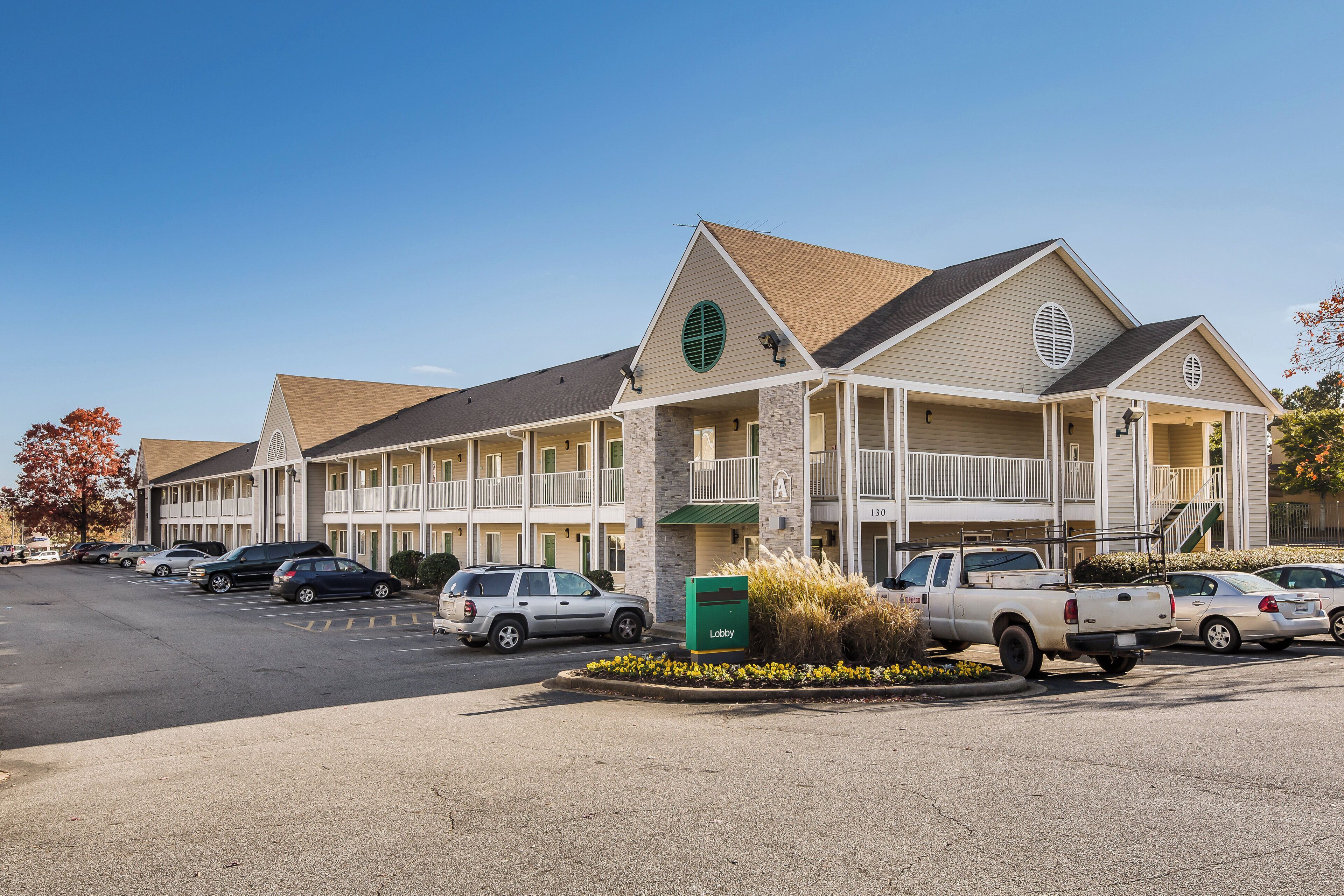 A motel with a two-story structure, a covered parking area, and a green mailbox.
