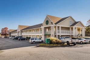 Um motel com estrutura em dois andares, área de estacionamento coberta e caixa de correio verde.