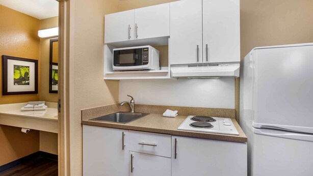 A compact kitchen with white cabinets, a microwave, a refrigerator, a sink, and a stove. - Extended Stay America Suites Nashville Brentwood South (Brentwood)