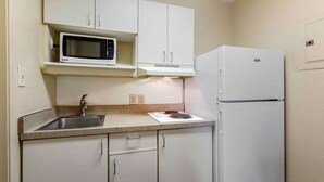 A compact kitchen with white cabinets, a microwave, a refrigerator, and a sink. - Extended Stay America Select Suites - Chattanooga - Airport (Chattanooga)