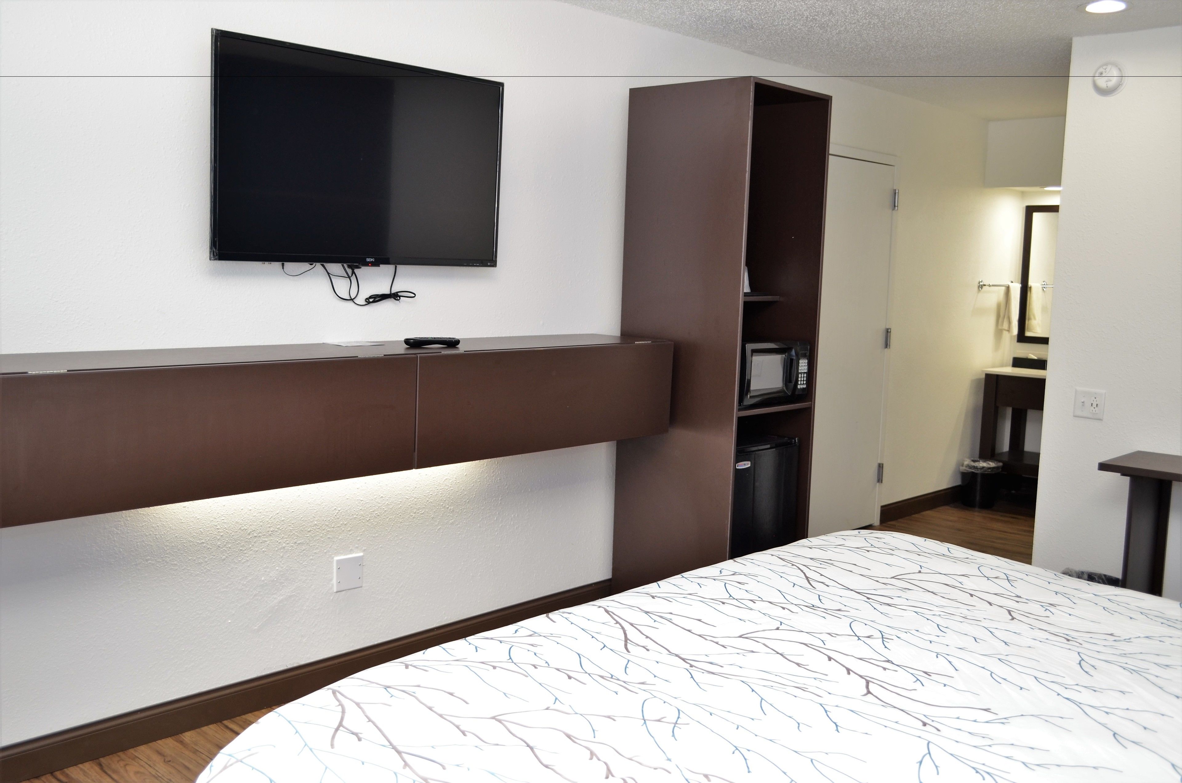 A hotel room with a large bed, a flat-screen TV mounted on the wall, and a built-in wardrobe.