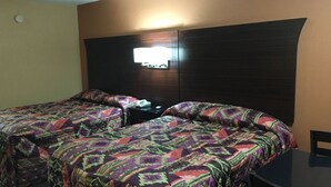 A double bed with patterned bedding, a bedside table with a lamp, and a wall-mounted TV. - Redwood Inn and Suites (White Hall)