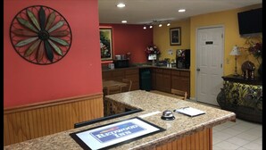 A kitchen with granite countertops, wooden cabinets, a refrigerator, and a microwave. There is a sign on the counter that reads "Redwood Inn." - Redwood Inn and Suites (White Hall)