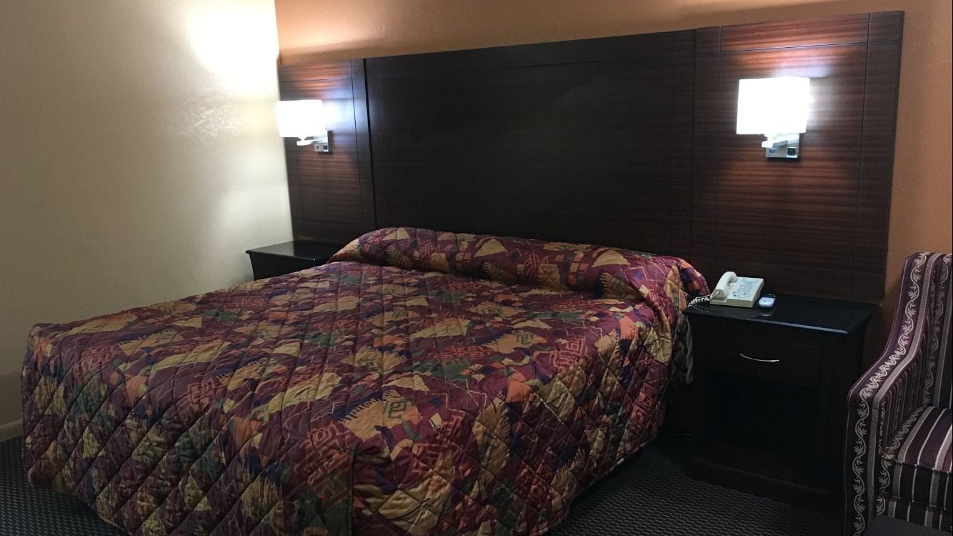 Una habitació d'hotel amb un llit gran, una taula de nit amb un telèfon i una cadira.