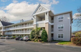 A multi-story hotel with a parking lot, balconies, and a central courtyard with trees.
