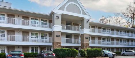 A multi-story hotel with a central lobby, multiple balconies, and a parking lot.