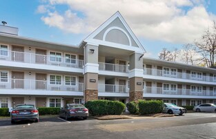 A multi-story hotel with a central lobby, multiple balconies, and a parking lot.