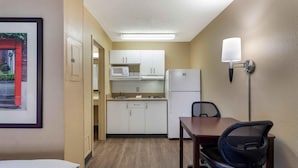 Une chambre d’hôtel compacte comprenant un coin cuisine, un espace repas avec une table et des chaises, et un lit.