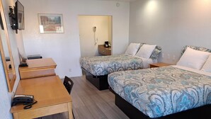 A hotel room with two beds, a desk, a chair, a telephone, and a small table. - Rodeway Inn Alameda-Oakland (Alameda)