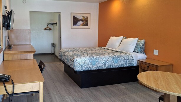 A hotel room with a bed, a desk, a chair, and a small table. - Rodeway Inn Alameda-Oakland (Alameda)