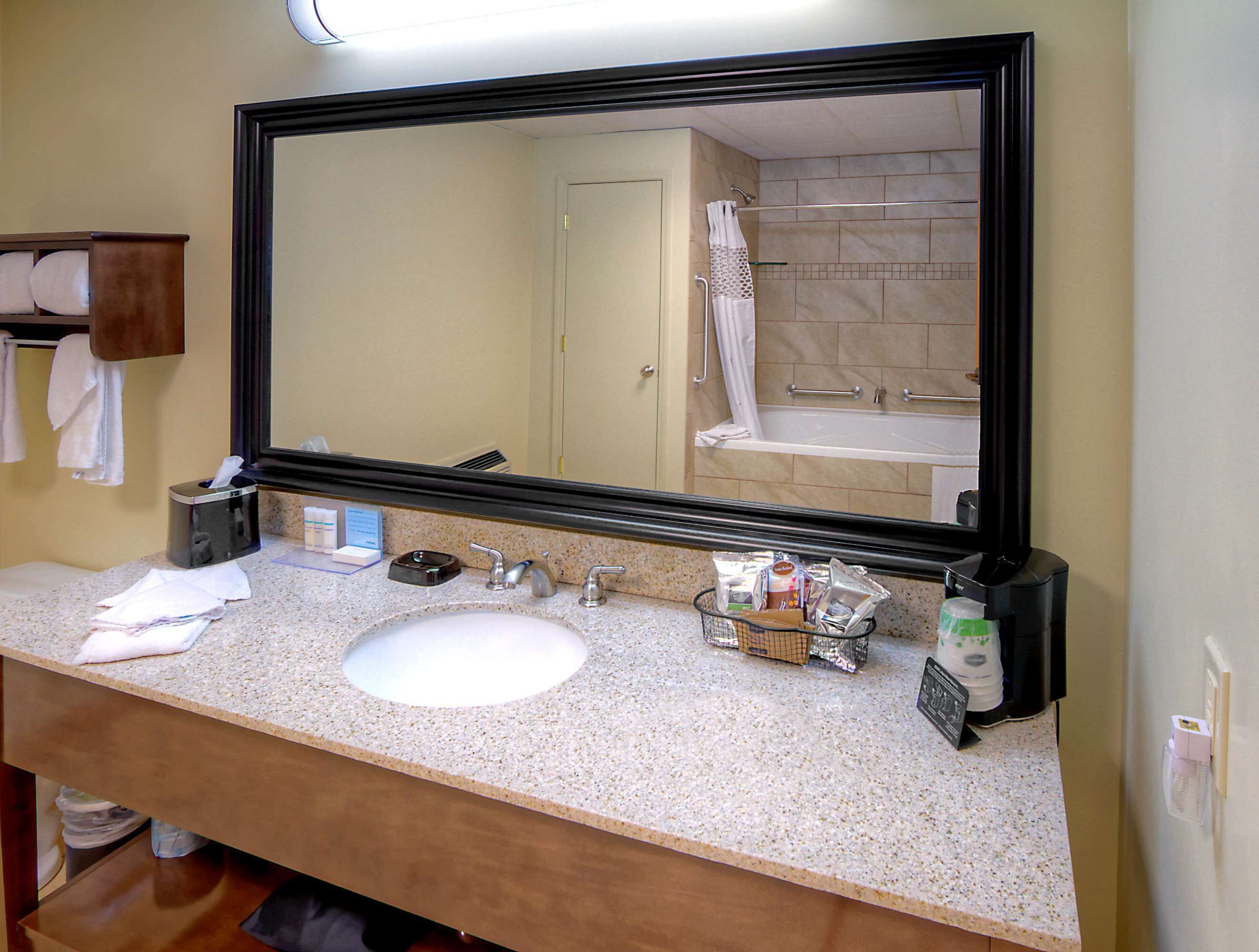 A bathroom with a sink, mirror, and toiletries.