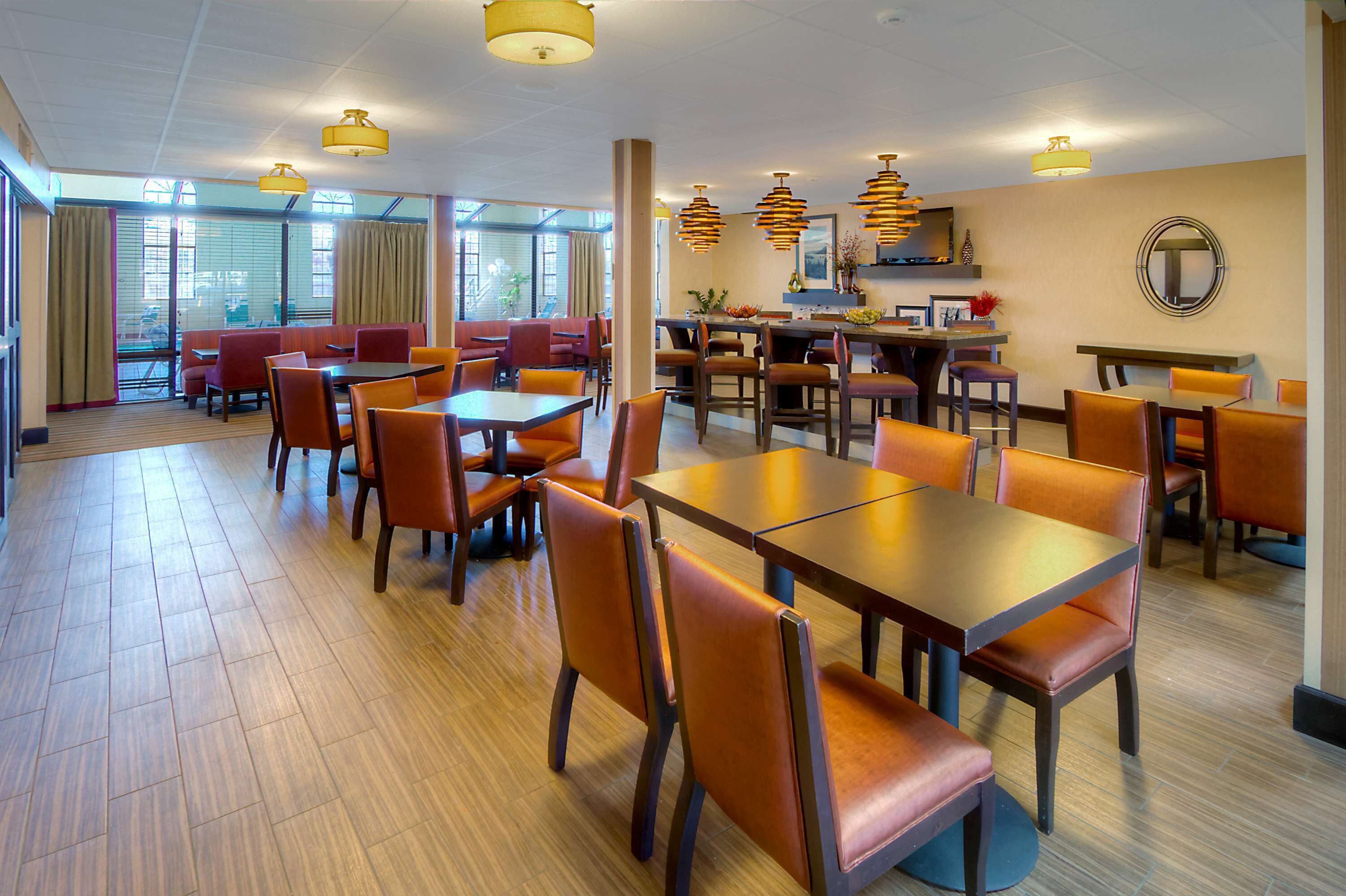 Un comedor de hotel con varias mesas y sillas, ventanas amplias y vistas al exterior.