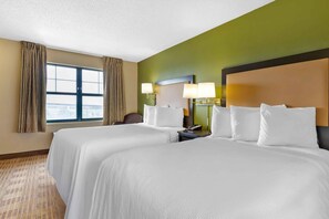 Two spacious beds with white linens, each flanked by a nightstand and lamp, offer a comfortable retreat with a view.