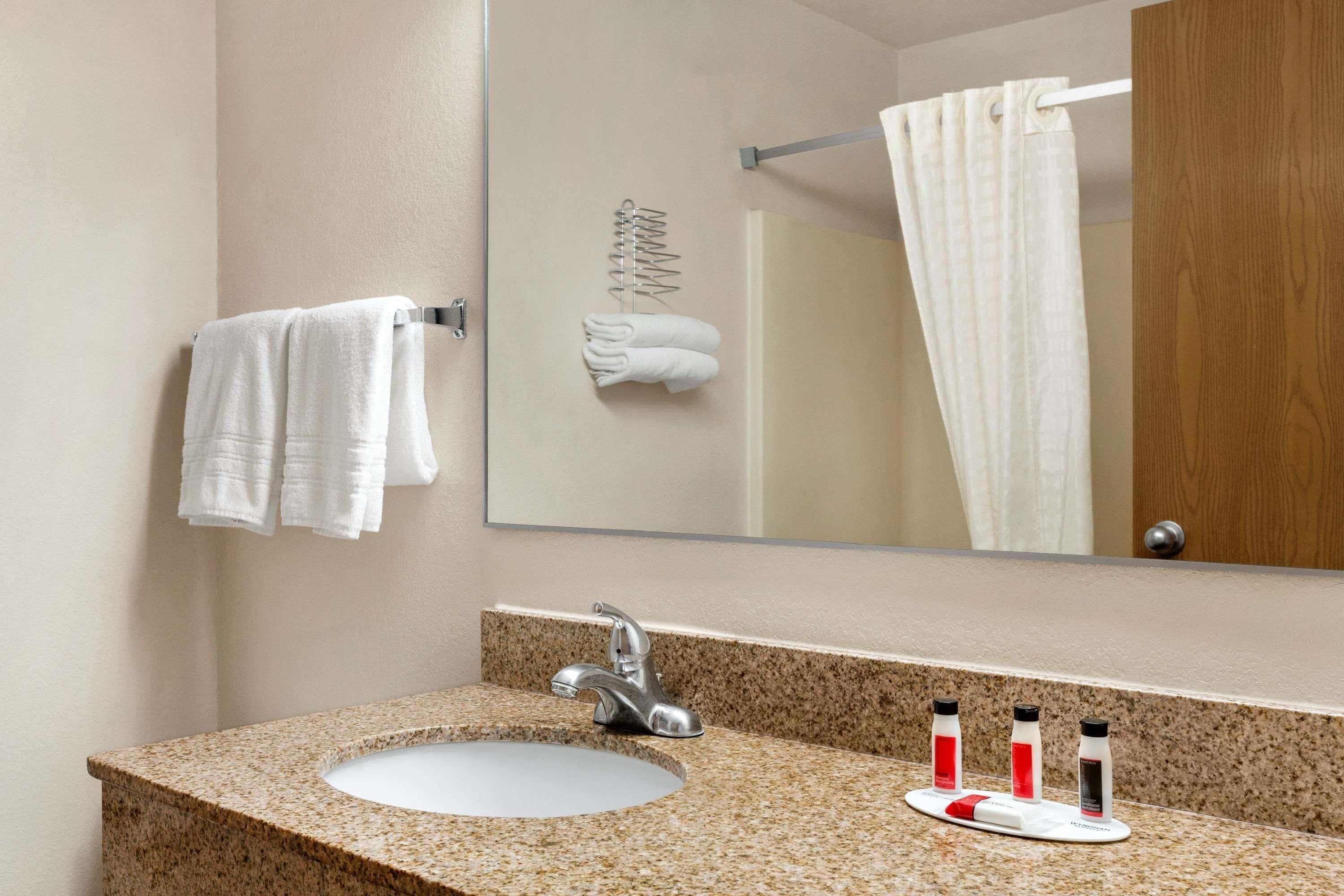 Un baño con lavamanos de encimera de granito, un espejo y un perchero para toallas.