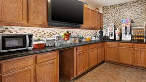 Una cucina con mobili in legno, un forno a microonde, un tostapane e una macchina per il caffè.