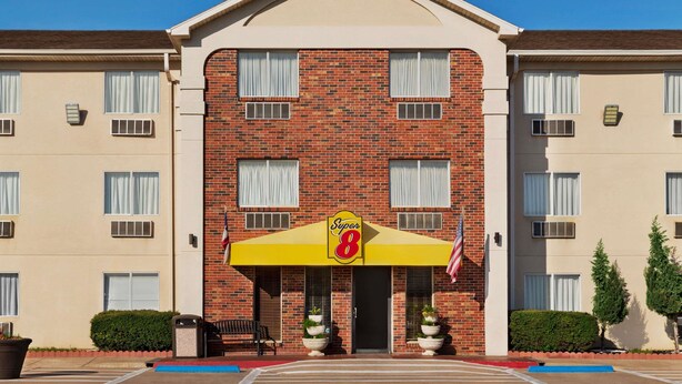 A hotel with a brick facade, a yellow awning with the number 8, and an American flag. - Super 8 by Wyndham Waco University Area (Waco)