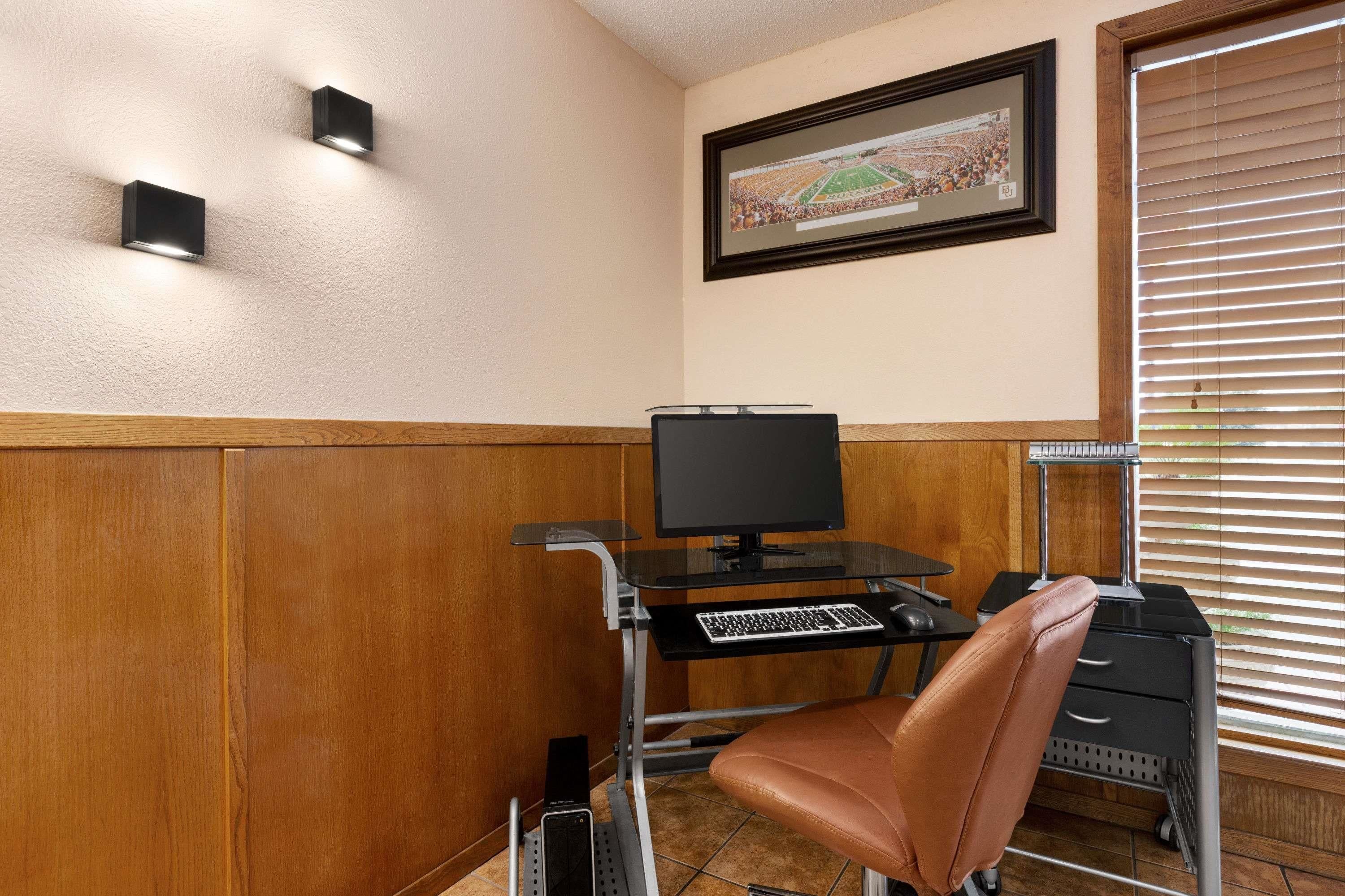 Une pièce comprenant un bureau, un ordinateur, une chaise et un tableau encadré accroché au mur.