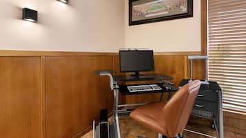 Una habitación con un escritorio, computadora, silla y un cuadro en la pared.